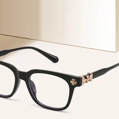 Black rectangular glasses frames with a small gold emblem on the hinge